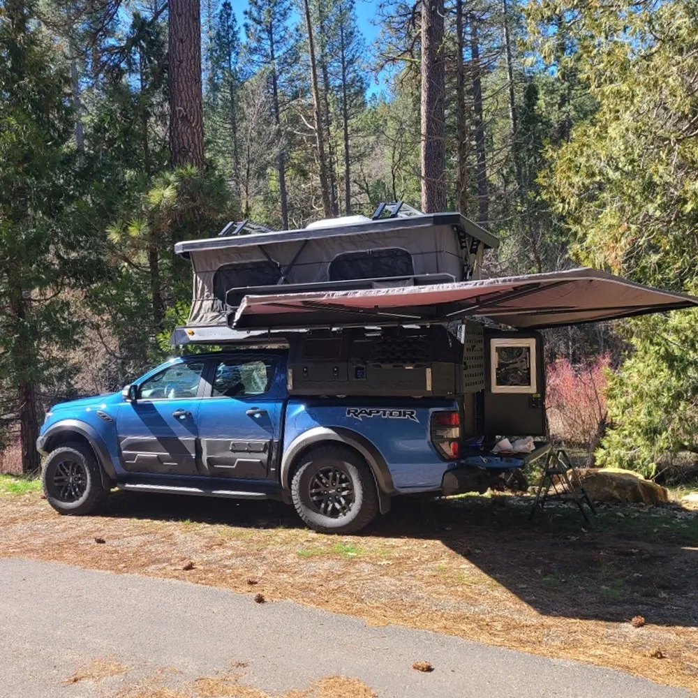forest camping, truck awning, overland campsite, blue truck, outdoor lifestyle, vehicle camping.