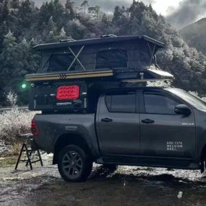 overland truck with rooftop tent in snowy mountains