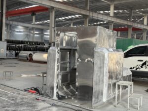 Welding workshop showing the raw metal body shell of a slide-in camper before insulation and painting.