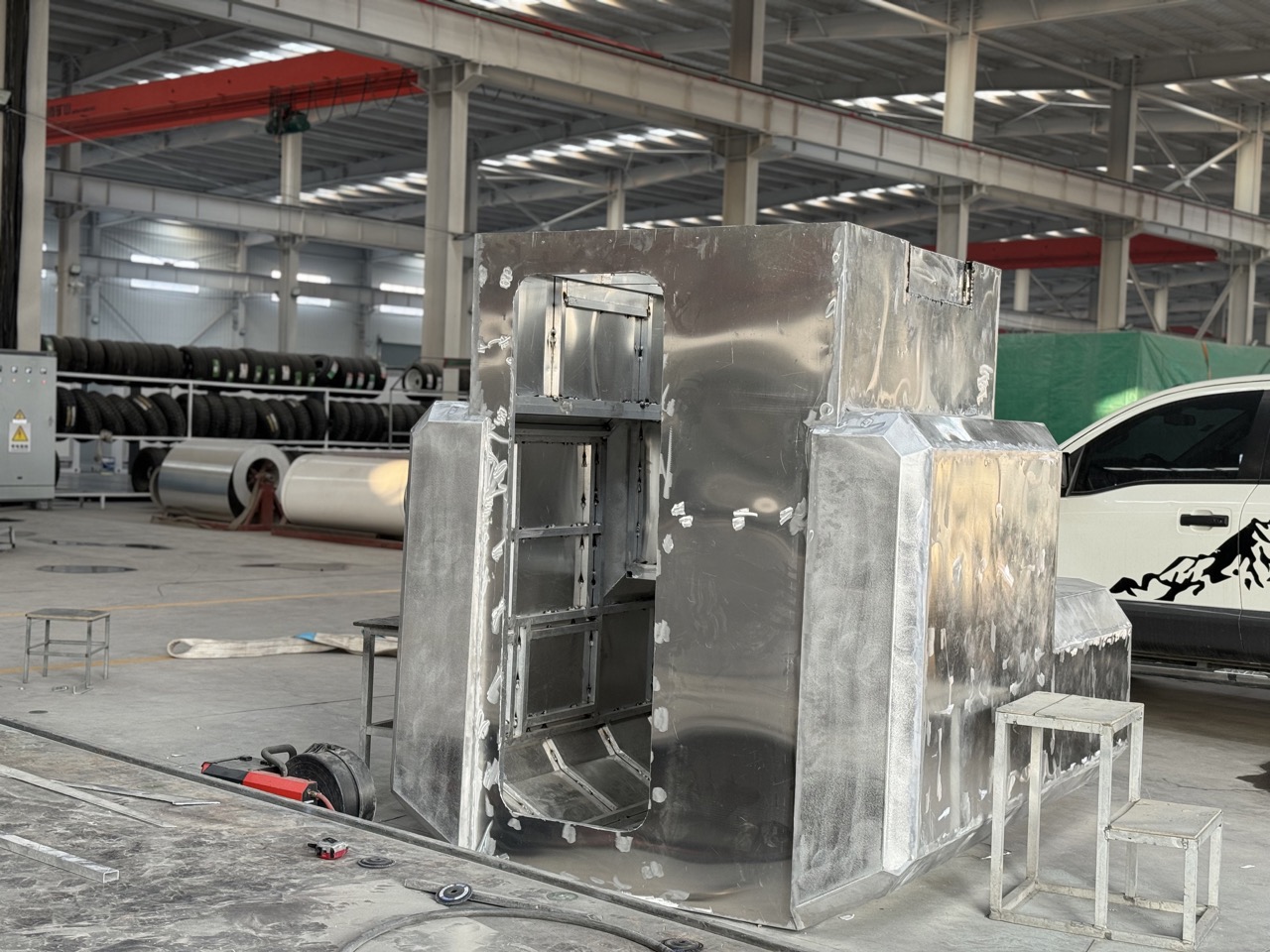 Welding workshop showing the raw metal body shell of a slide-in camper before insulation and painting.